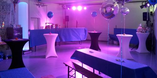 Mit Eventtechnik dekorierter Raum. Luftballons, Stehtische und Floorspots